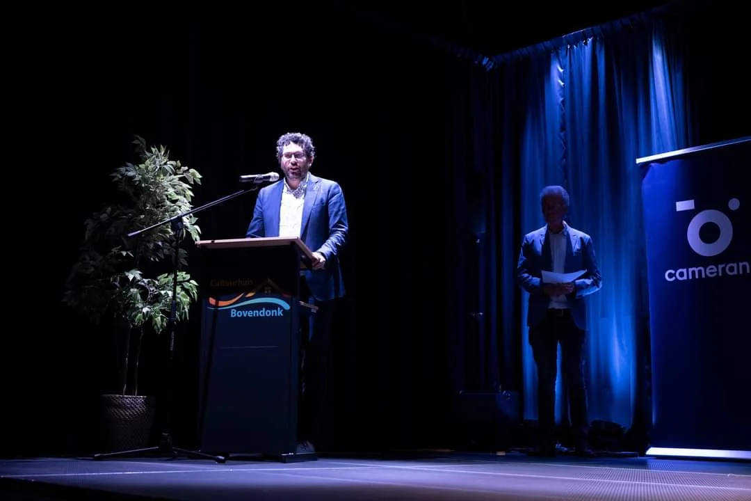 Arwen van Gestel spreekt ingetogen in een donkere zaal achter een katheder