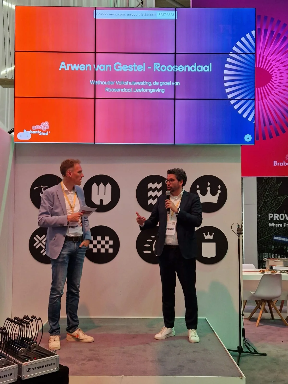 Arwen van Gestel spreekt op een congres met microfoon en groot scherm