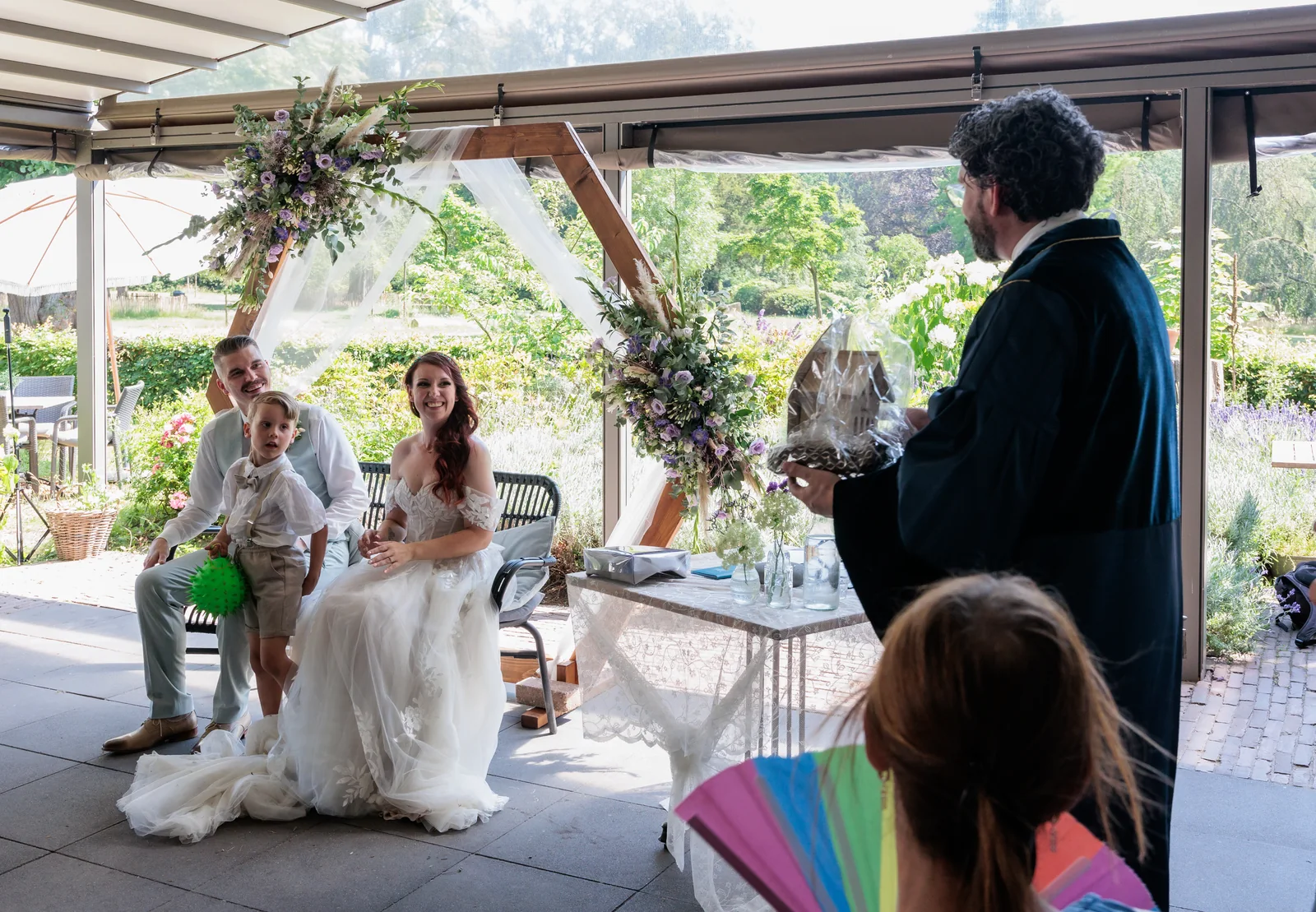 Arwen van Gestel spreekt een bruidspaar en hun gezin toe tijdens een trouwceremonie in de tuin